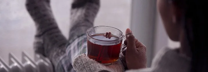 Person mit Socken und Tasse Tee